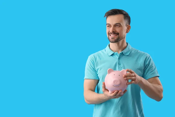 Bonito Homem Com Banco Porquinho Fundo Azul — Fotografia de Stock