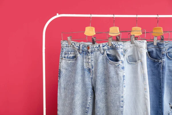 Rack Stylish Jeans Red Background Closeup — Stock Photo, Image