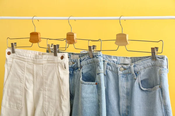 Rack Mit Stylischen Jeans Auf Gelbem Hintergrund Nahaufnahme — Stockfoto