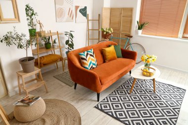 Işıl ışıl oturma odasının içinde rahat kahverengi kanepe ve sehpanın üzerinde narsist çiçekler.