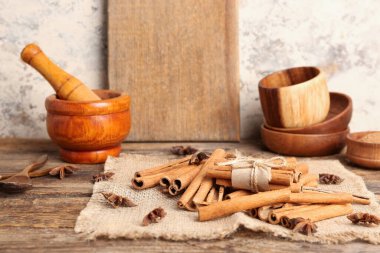 Bir yığın tarçın çubuğu, anason yıldızları ve mutfak gereçleri ahşap masada.
