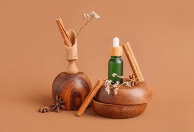 Gerekli yağ şişesi, tarçın çubukları, anason yıldızları ve arka planda ahşap tabaklarla kompozisyon