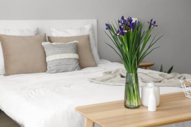 Komodinin üzerinde çiçek açan vazo.