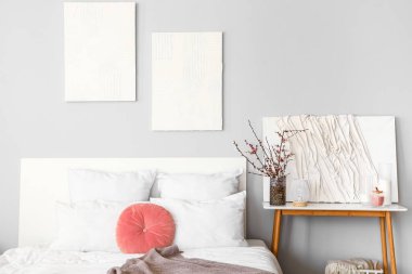 Yatak odasının içinde komodinin üzerinde çiçek açan ağaç dalları var.