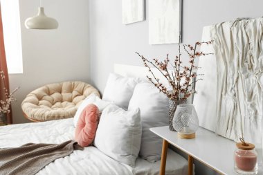 Komodinin üzerinde çiçek açan ağaç dalları olan vazo.