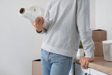 Genç adam mutfakta streç film çekiyor, yakın plan.