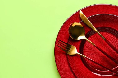 Yeşil zemin üzerinde temiz tabak ve çatal bıçak takımı olan masa ayarları