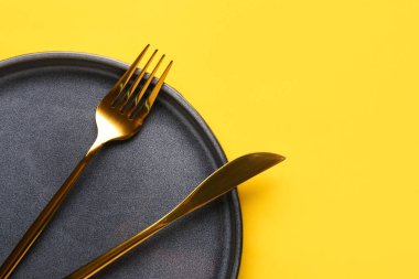Sarı zemin üzerinde temiz tabak ve çatal bıçak takımı olan masa ayarları