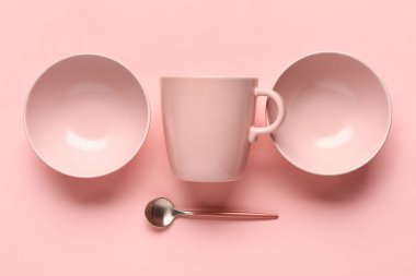 Temiz kaselerle kompozisyon, pembe arka planda fincan ve kaşık.