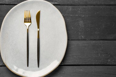 Masa seti, temiz tabak ve siyah ahşap masa üzerine çatal bıçak.