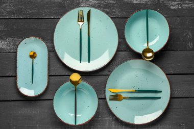 Masa seti, temiz tabaklar ve siyah ahşap masa üzerine çatal bıçak.