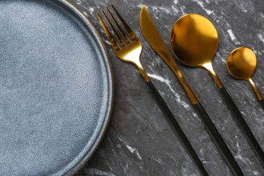 Gri grunge masa üzerinde temiz tabak ve çatal bıçak seti, yakın plan.