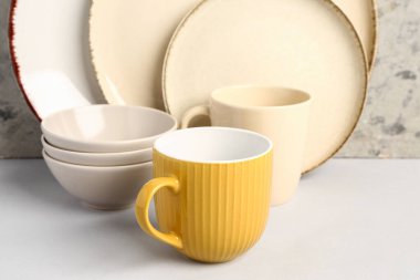 Gri grunge duvarın yanındaki masada farklı tabaklar var.