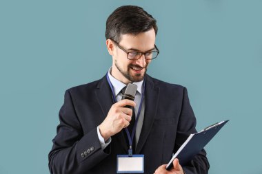 Mavi arka planda mikrofonu ve panosu olan erkek gazeteci