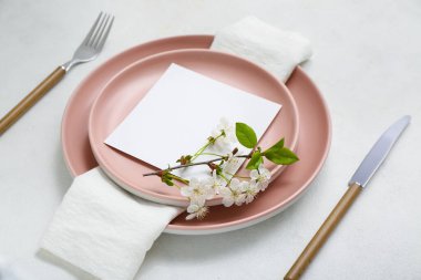 Boş davetiye kartıyla güzel masa ayarları ve beyaz masanın üzerinde çiçek açan ağaç dalı