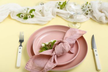 Sarı arka planda çiçek açan ağaç dalları olan güzel bir masa.