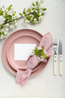 Çiçek açan ağaç dalları ve beyaz arkaplanda boş davetiye kartı olan güzel masa ayarları