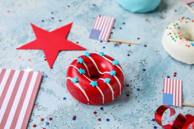 Composition with donuts, USA flags and confetti on blue grunge table. Independence Day celebration clipart