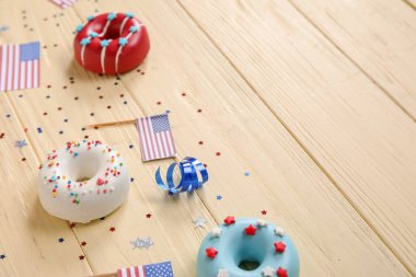 Donutlu kompozisyon, Amerikan bayrakları ve sarı ahşap masada konfeti. Bağımsızlık Günü kutlamaları