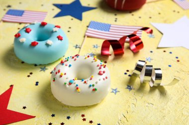 Donutlu kompozisyon, sarı masada Amerikan bayrakları ve konfeti. Bağımsızlık Günü kutlamaları