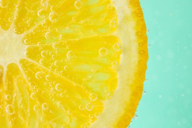 Turkuaz arka planda baloncuklu limon dilimi