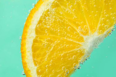 Turkuaz arka planda baloncuklu portakal dilimi