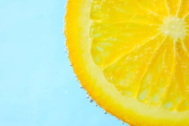 Mavi zemin üzerinde kabarcıklar olan sudaki portakal dilimi