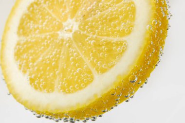 Beyaz zemin üzerinde kabarcıklar olan limon dilimi