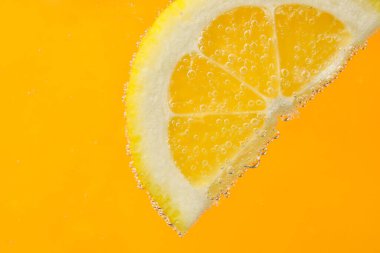 Limon dilimleri ve turuncu arka planda kabarcıklar.