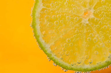 Limon dilimleri ve turuncu arka planda kabarcıklar.