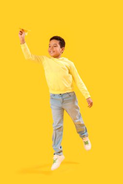 Sarı arka planda kağıt uçaklı küçük Afro-Amerikalı çocuk. Çocuk Bayramı kutlaması