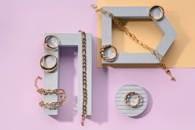 Renk arkaplanında altın yüzüklü ve bilezikli kaideleri göster