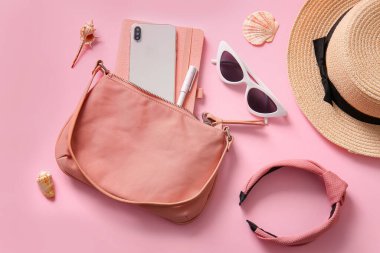 Cep telefonlu şık çanta ve pembe arka planda farklı aksesuarlar.