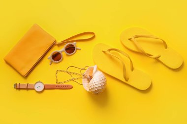 Saati olan şık bir çanta ve sarı arka planda farklı aksesuarlar.