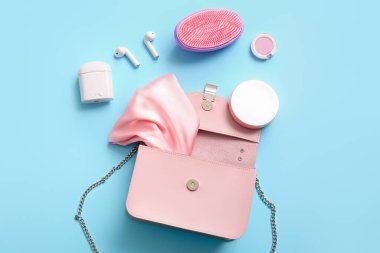 Kulaklıklı şık bir çanta ve mavi arka planda farklı aksesuarlar.