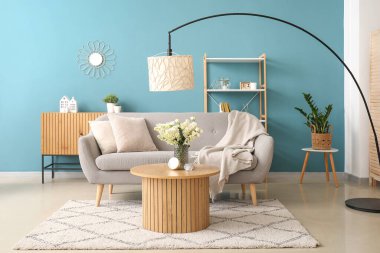 Gri kanepesi ve sehpasında leylak çiçekleri olan şık bir oturma odası.