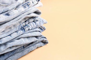 Soluk turuncu arka planda farklı şık kot pantolon yığını