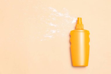 Soluk turuncu arka planda bir şişe güneş kremi.