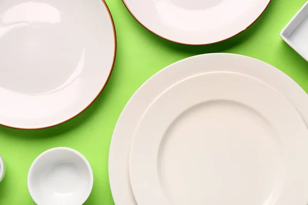 Komposition Mit Sauberen Tellern Und Schalen Auf Grünem Hintergrund — Stockfoto