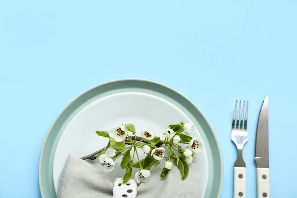 stock image Beautiful table setting with folded napkin and blooming tree branch on turquoise background