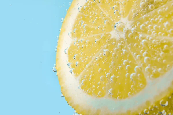 青の背景に泡と水でレモンスライス — ストック写真