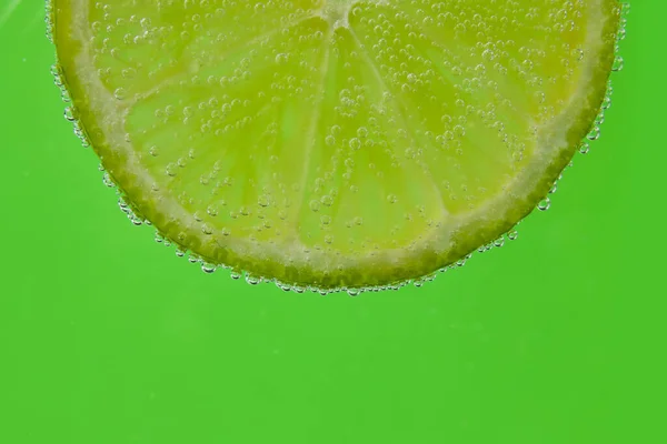 緑の背景に泡と水でレモンスライス — ストック写真