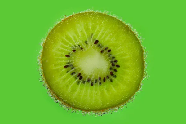 Kiwi Plasterek Wodzie Bąbelkami Zielonym Tle — Zdjęcie stockowe
