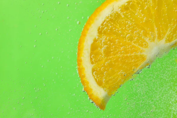 緑の背景に泡と水のオレンジスライス — ストック写真