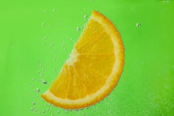 緑の背景に泡と水のオレンジスライス — ストック写真