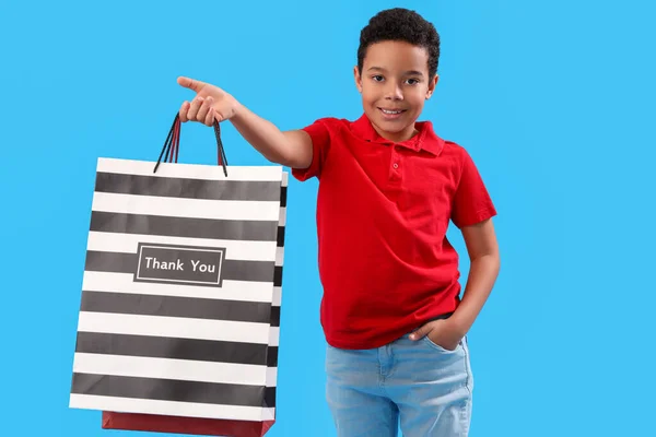 青い背景にショッピングバッグを持つ小さなアフリカ系アメリカ人の少年 こどもの日 — ストック写真
