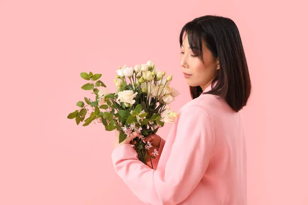 stock image Beautiful Asian woman holding bouquet of eustoma flowers on pink background