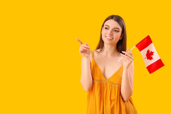 Młoda Kobieta Flagą Kanady Wskazującą Coś Żółtym Tle — Zdjęcie stockowe