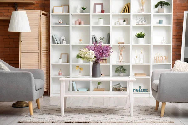 stock image Interior of living room with cozy armchairs and beautiful lilac flowers on coffee table