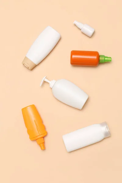 Different bottles of sunscreen cream on pale orange background